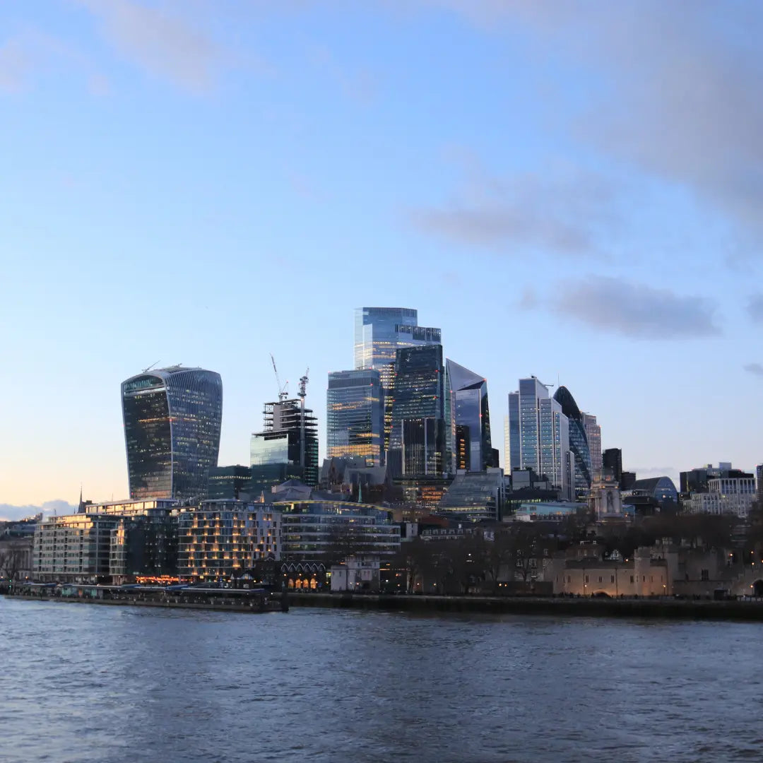 A photo of Canary Wharf in London with a clear, sun-setting sky above the famous buildings of London