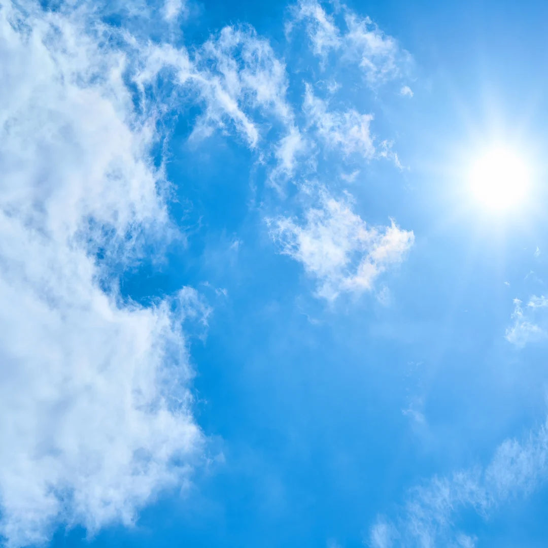 An image of a blue, bright and clear sky with the shining sun on the left hand side of the image